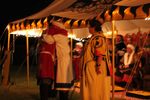 Their Majesties speak a few words at the closing of Evening Court at Namron Protectorate, acknowledging this is Their final Court prior to step-down. Master Cassius Domitius Lepus, Lion of Ansteorra, entered court unbidden, to give them a hug. Photo by Zubeydah. October 2019.